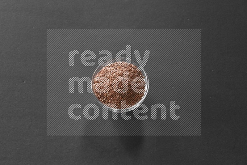 A glass bowl full of flax on black flooring