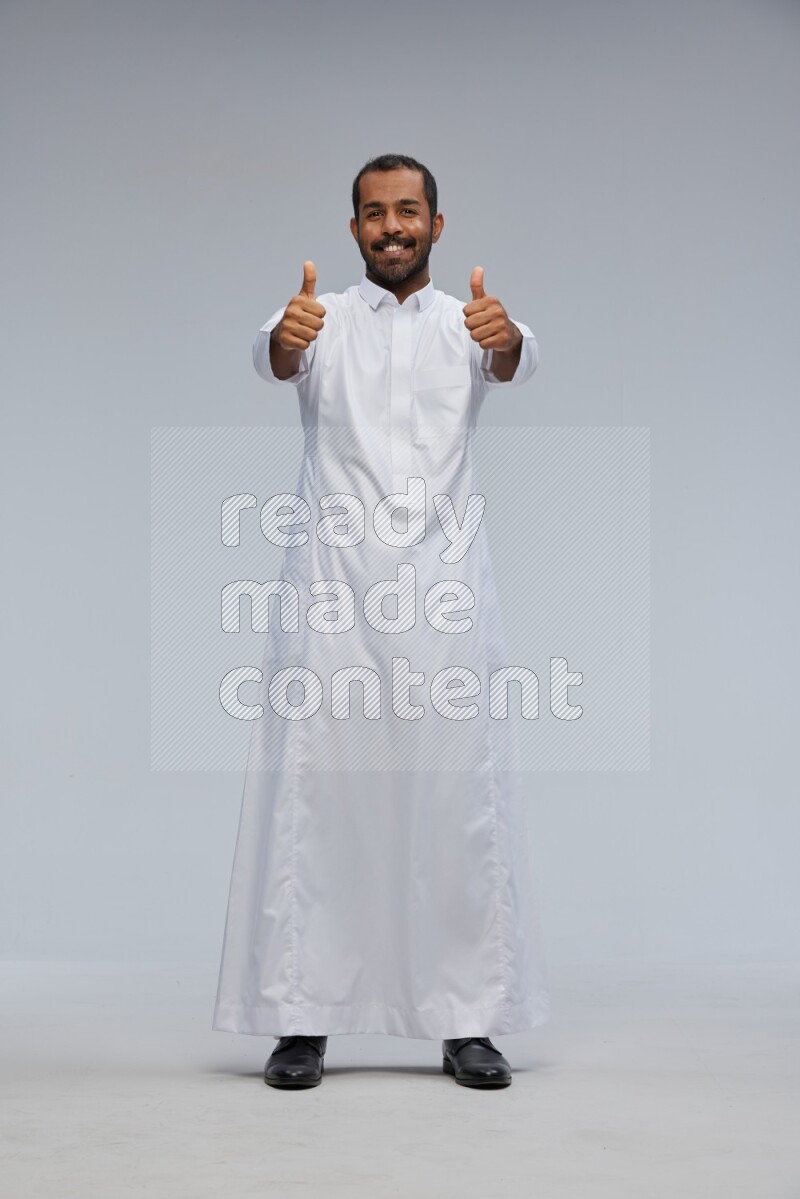 Saudi man Wearing Thob standing interacting with the camera on Gray background