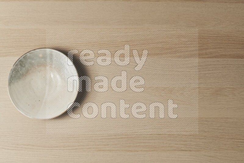 A multicolored pottery plate on light wooden background