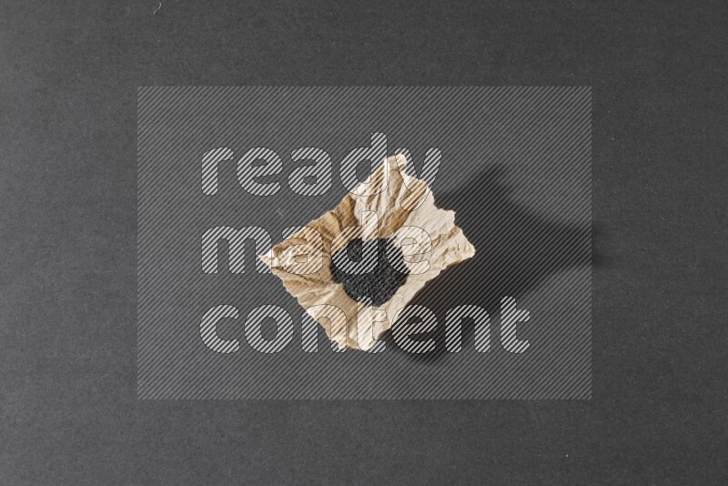 بذور حبة البركة في قطعة من الورق علي خلفية سوداء