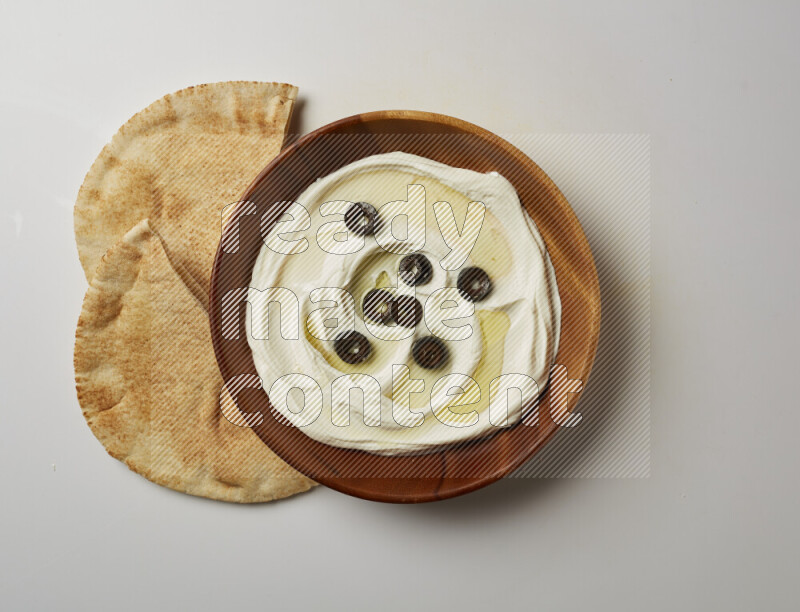 Lebnah garnished with sliced olives in a wooden plate on a white background
