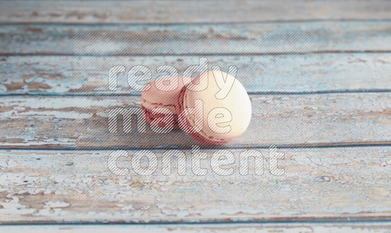 45º Shot of two Pink Litchi Raspberry macarons on light blue wooden background