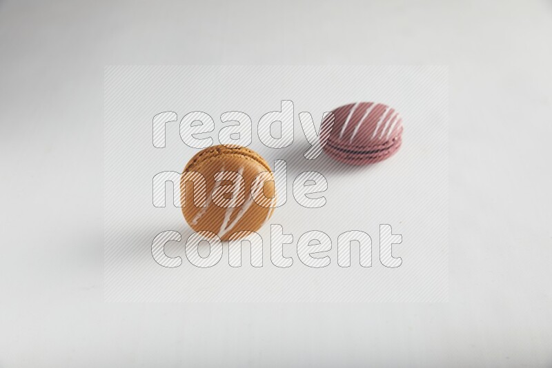 45º Shot of of two assorted Brown Irish Cream, and Red Poppy Flower macarons on white background