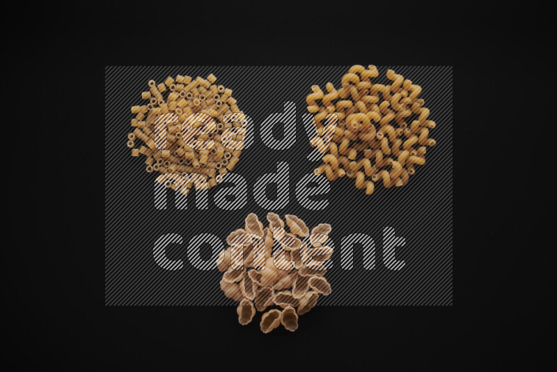 Different pasta types in bunches on black background