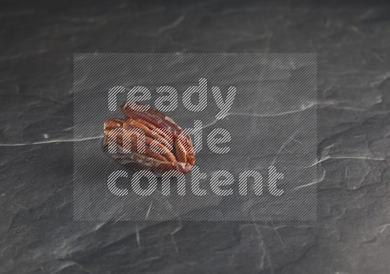 pecan stuffed madjoul date on a black textured background