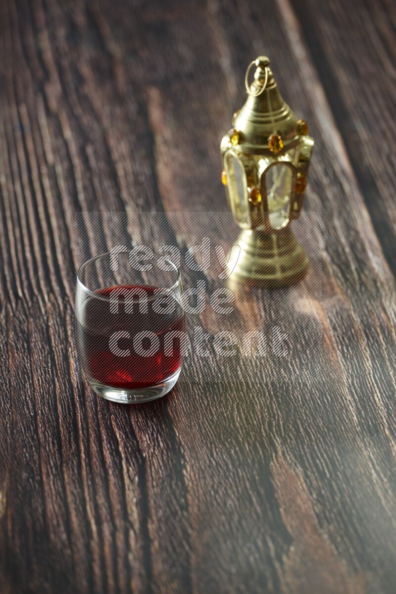 A golden lantern with different drinks, dates, nuts, prayer beads and quran on brown wooden background