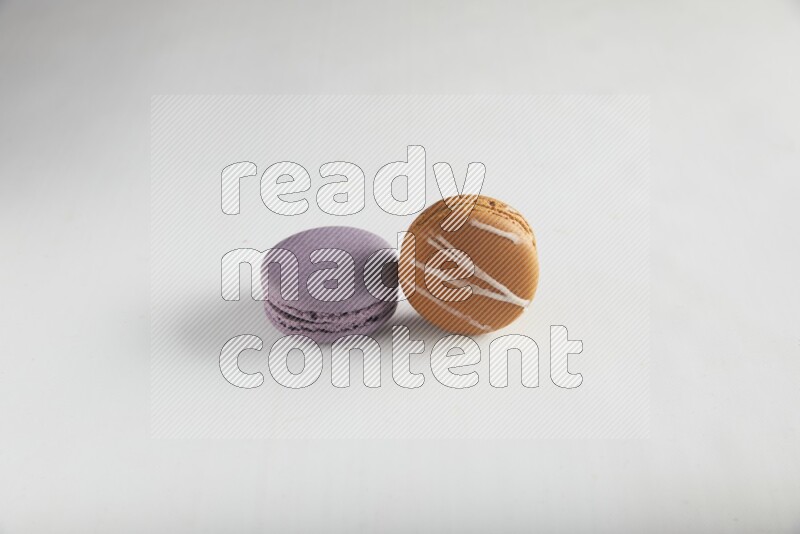 45º Shot of of two assorted Brown Irish Cream, and Purple Blueberry macarons on white background