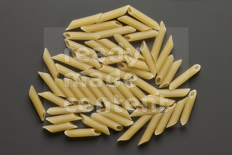 Mini penne pasta on grey background