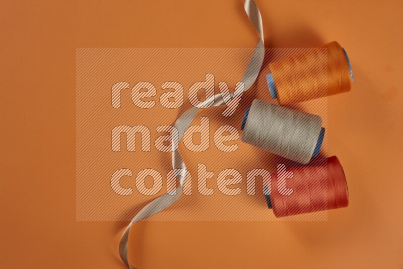 A brown collection of sewing and tailoring tools arranged on a orange background