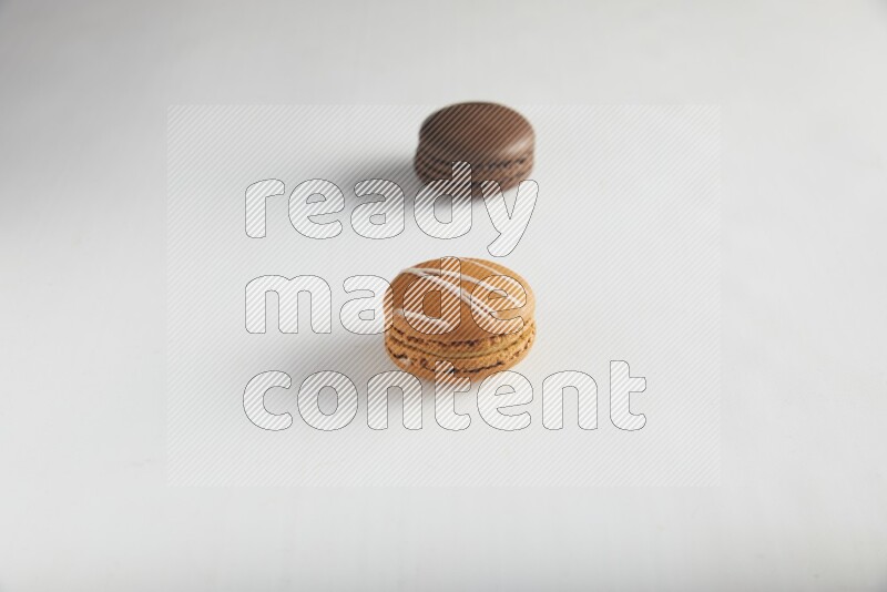 45º Shot of of two assorted Brown Irish Cream, and Brown Dark Chocolate macarons on white background