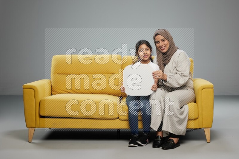 Mom and daughter sitting holding social media sign on gray background