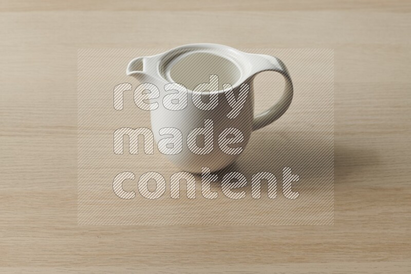 A ceramic milk jug on light wooden background