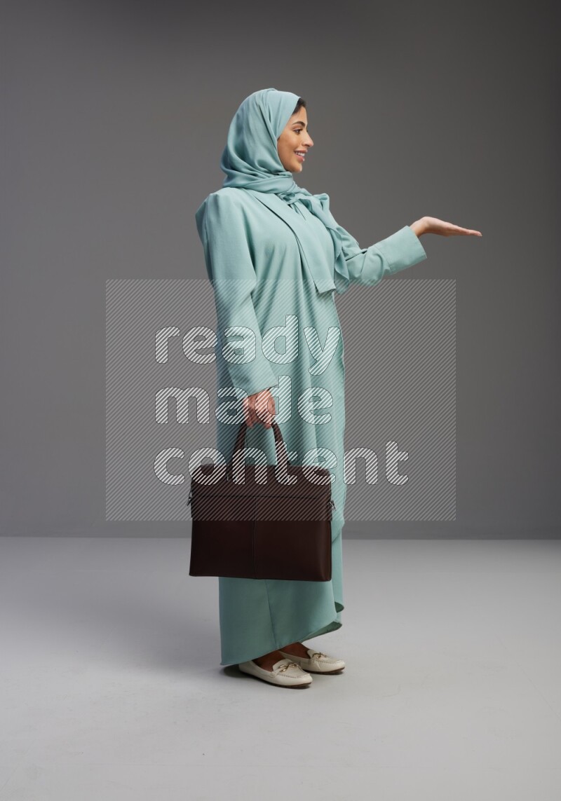 Saudi Woman wearing Abaya standing holding bag on Gray background