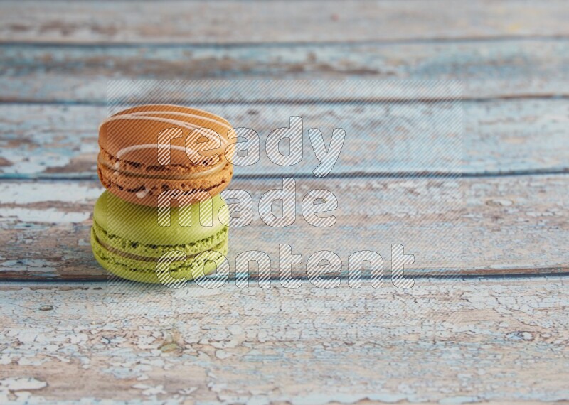 45º Shot of of two assorted Brown Irish Cream, and Green Pistachio macarons  on light blue background