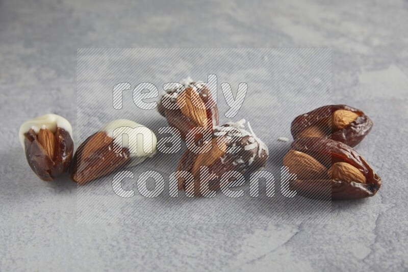 Group of Almonds stuffed dates plain and covered with chocolate on a light grey background