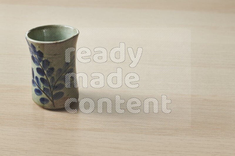 A pottery cup on light wooden background