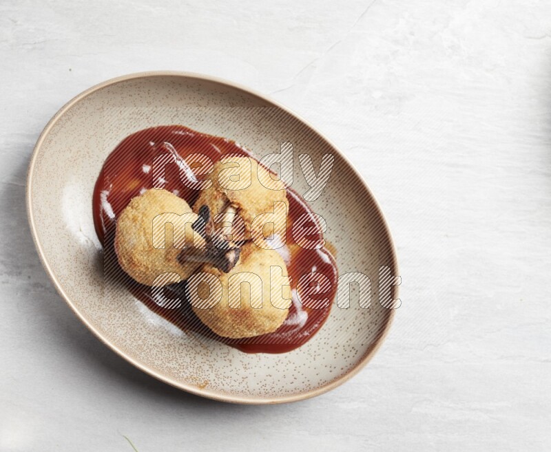 breaded drumstick on oval beige pottery plate on grey textured countertop