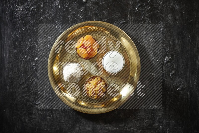 Dried fruits in metal bowls with sobya on a tray in dark setup