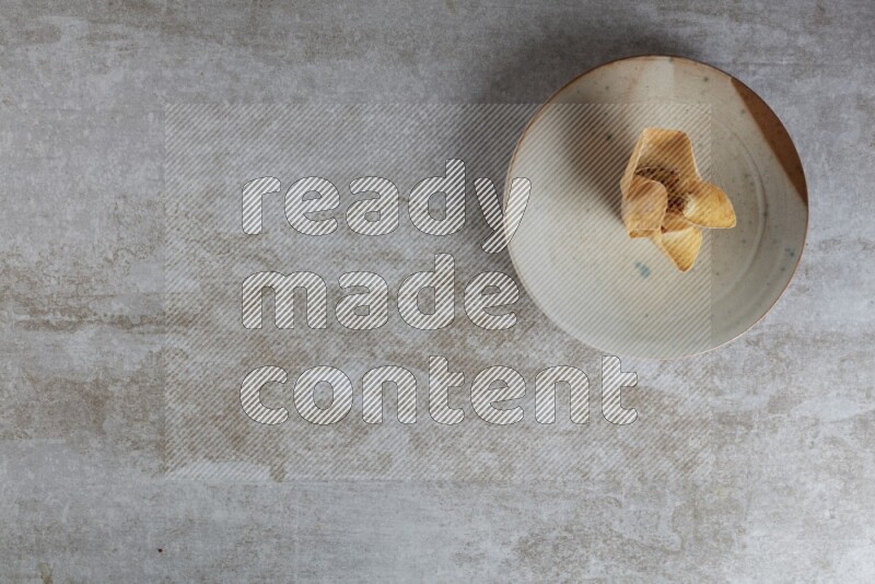 wonton cups with soy sauce ramkin on multi colored pottery on grey textured counter top