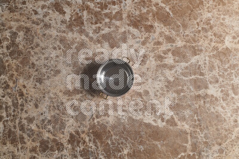 A small copper pot on beige marble background
