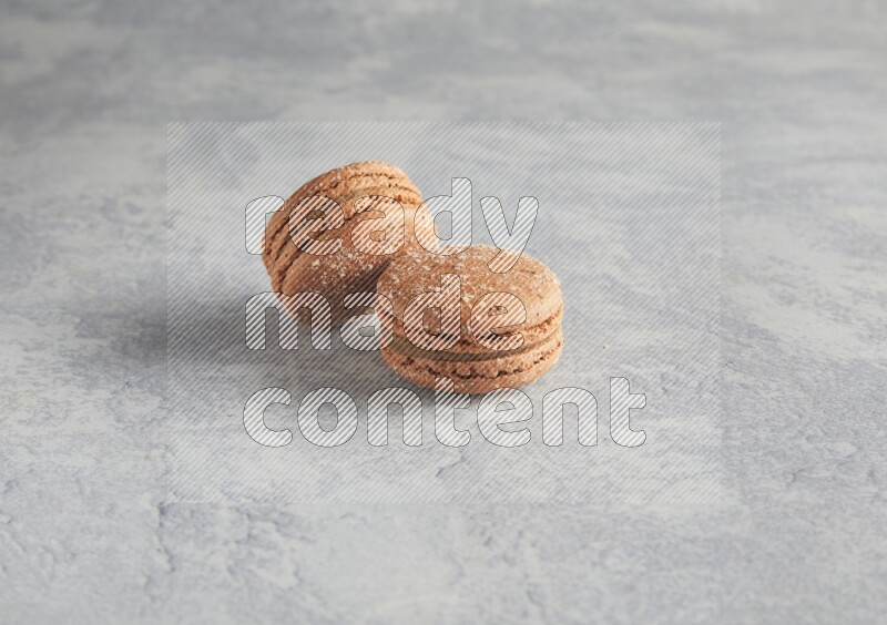 45º Shot of two Brown Hazelnuts macarons  on white  marble background