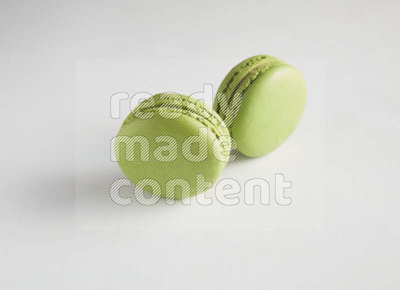 45º Shot of two Green Pistachio macarons on white background