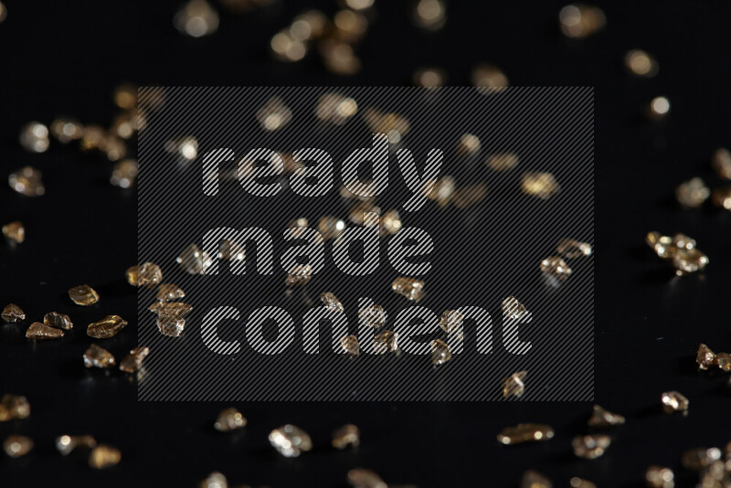 Gold shimmering fragments of glass scattered on a black background