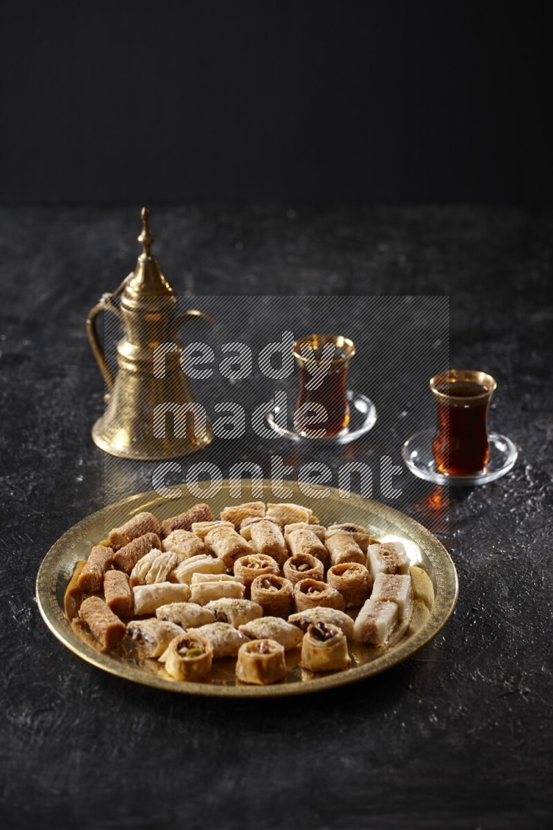 Oriental desserts with tea and a metal pot in a dark setup