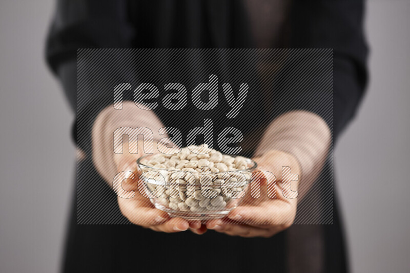 Woman in abaya holding different kinds of legumes in different positions