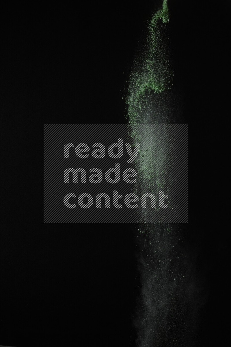 A side view of green powder explosion on black background