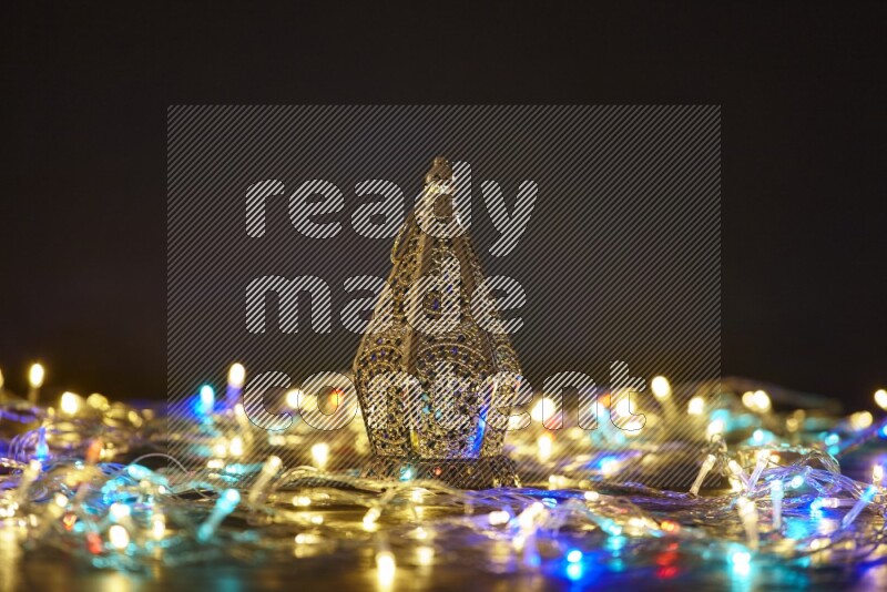 A traditional ramadan lantern surrounded by glowing fairy lights in a dark setup