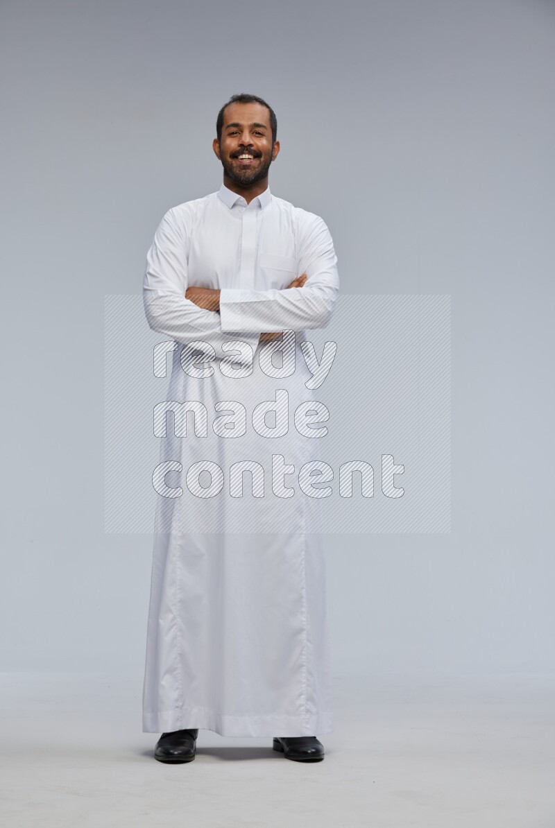 Saudi man wearing Thob standing with crossed arms on Gray background