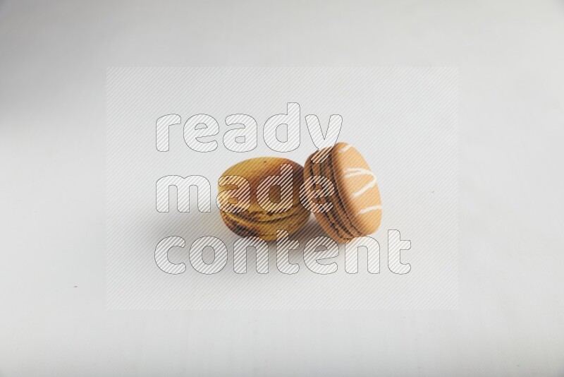 45º Shot of of two assorted Brown Irish Cream, and Yellow Crème Brulée macarons on white background