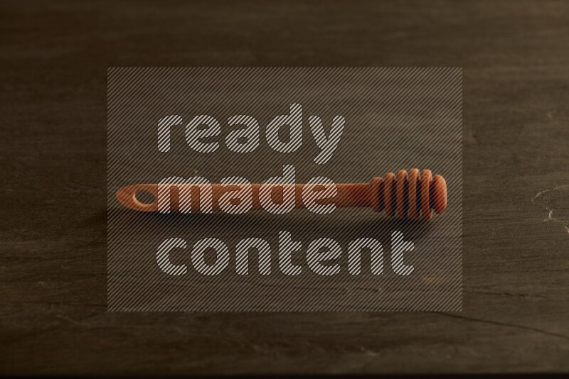 Wooden honey dipper on black slate background