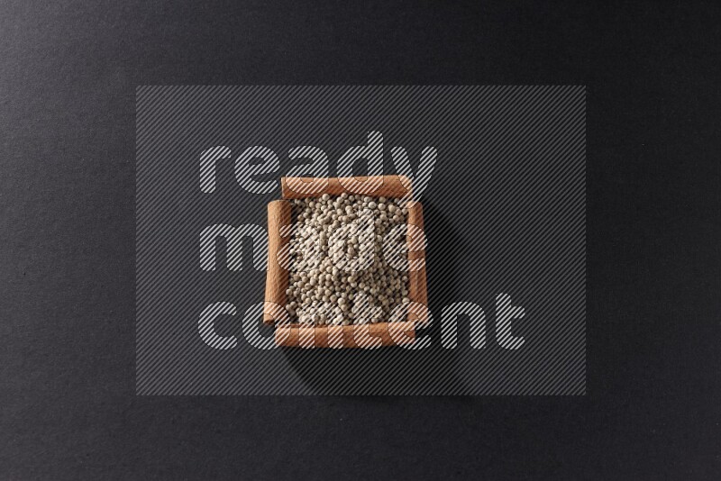 A single square of cinnamon sticks full of white pepper on black flooring
