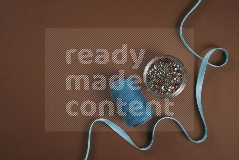 A blue collection of sewing and tailoring tools arranged on a brown background