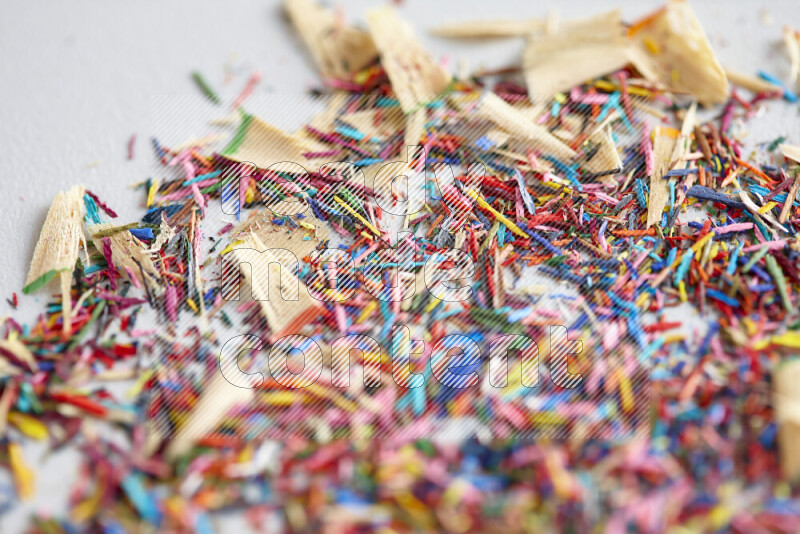 This image showcases a vibrant multicolored pencil shavings scattered on grey background
