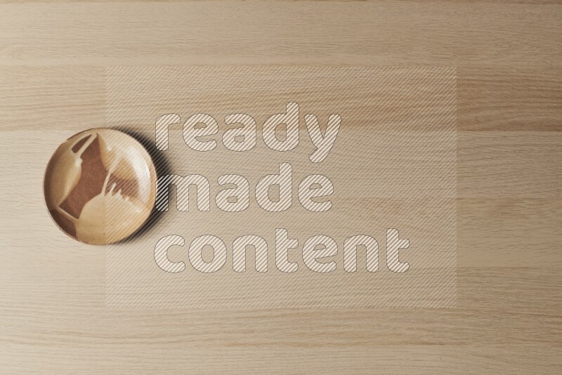A multicolored pottery plate on light wooden background