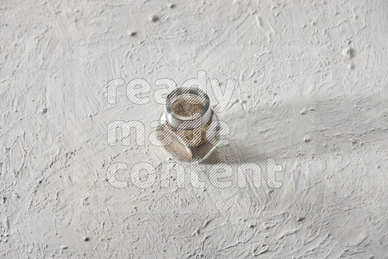 فلفل أسود مطحون في وعاء زجاجي علي خلفية بيضاء