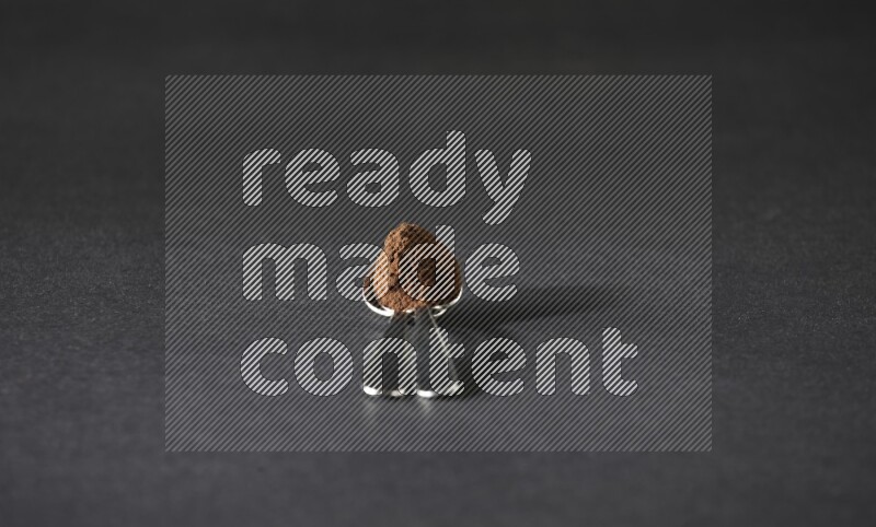 ملعقتان معدنيتان فوق بعضهما البعض ممتلئتان ببودرة القرنفل على أرضية سوداء