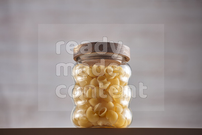 Raw pasta in glass jars on beige background