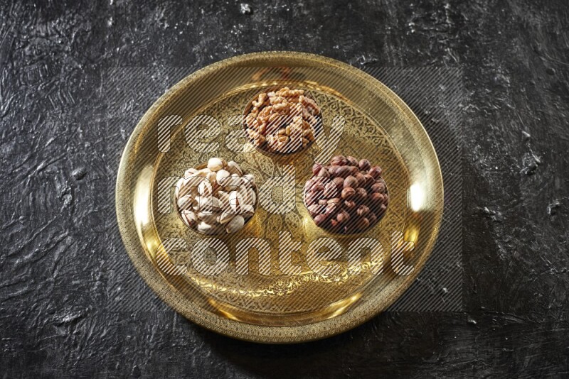 Nuts in metal bowls on a tray in a dark setup