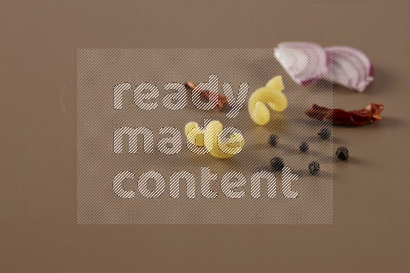 معكرونة مع مكونات متنوعة من الطماطم والثوم والبصل والفلفل الأحمر والفلفل الأسود والفلفل الأبيض وأوراق الغار وإكليل الجبل والهيل على خلفية بيج