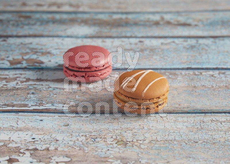 45º Shot of of two assorted Brown Irish Cream, and Pink Raspberry macarons on light blue background