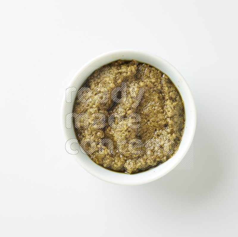 Large white ceramic oval bowl filled with pesto paste on a white counter top