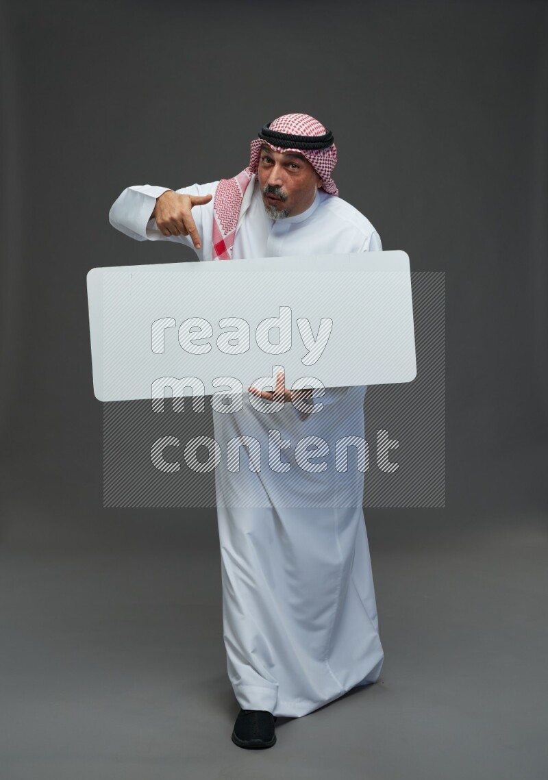 Saudi man with shomag Standing holding social media sing on gray background