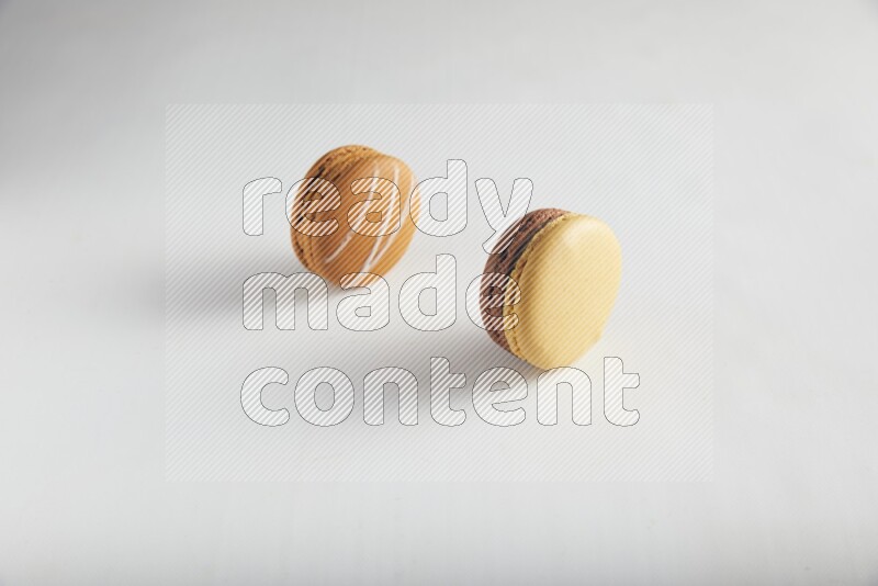 45º Shot of of two assorted Brown Irish Cream, and Yellow, and Brown Chai Latte macarons on white background