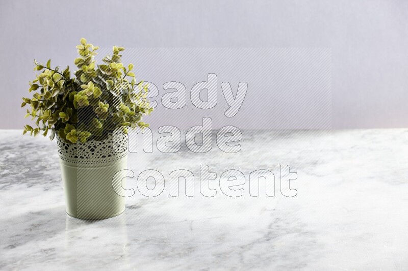 Artificial plant in green decorative pot on grey marble background