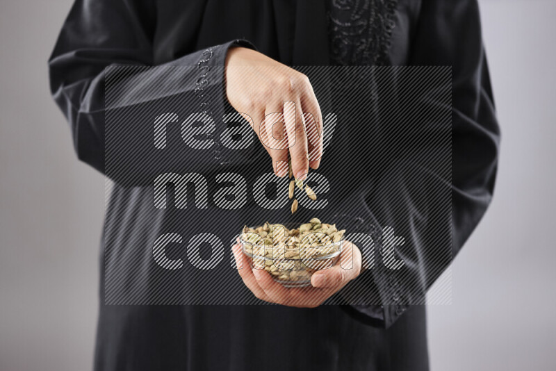 Woman in abaya holding different kinds of spices in different positions