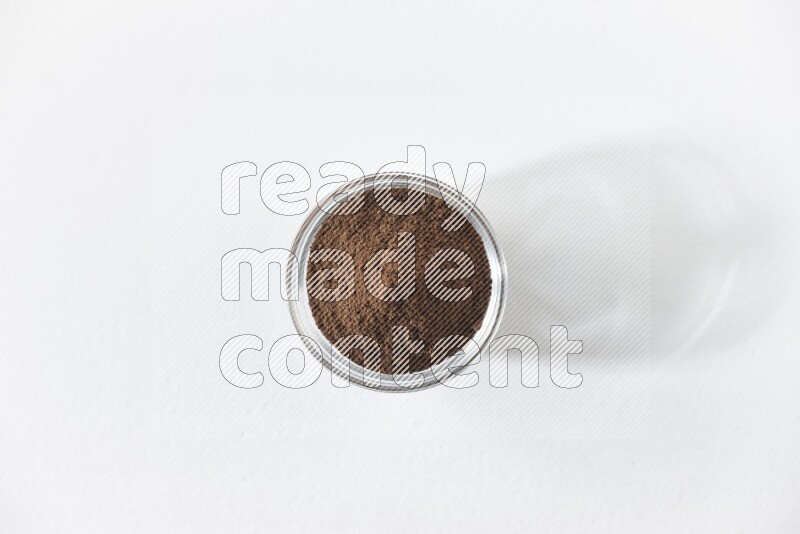 A glass bowl full of cloves powder on white flooring